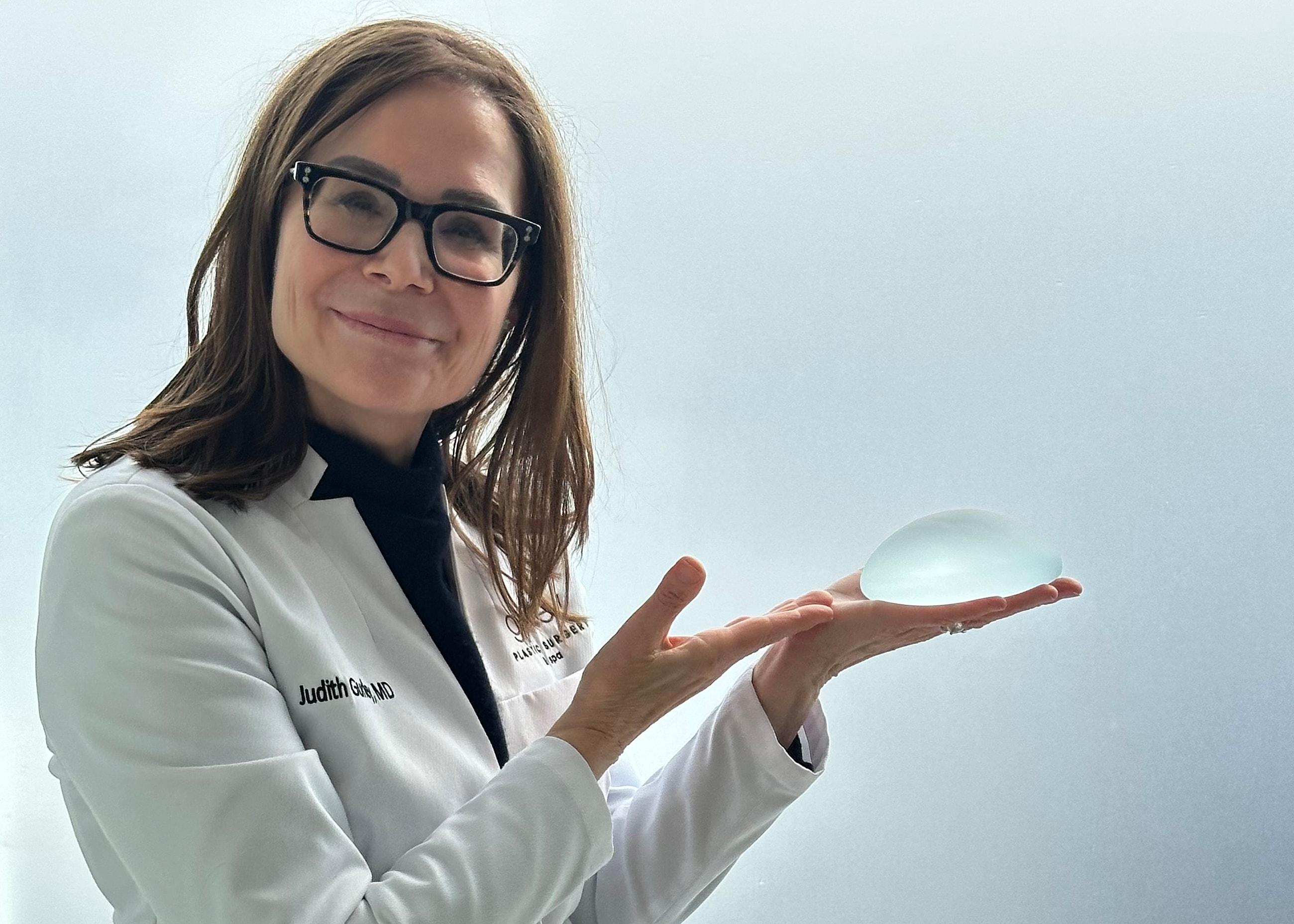 Medical professional examining abdomen with metal device.